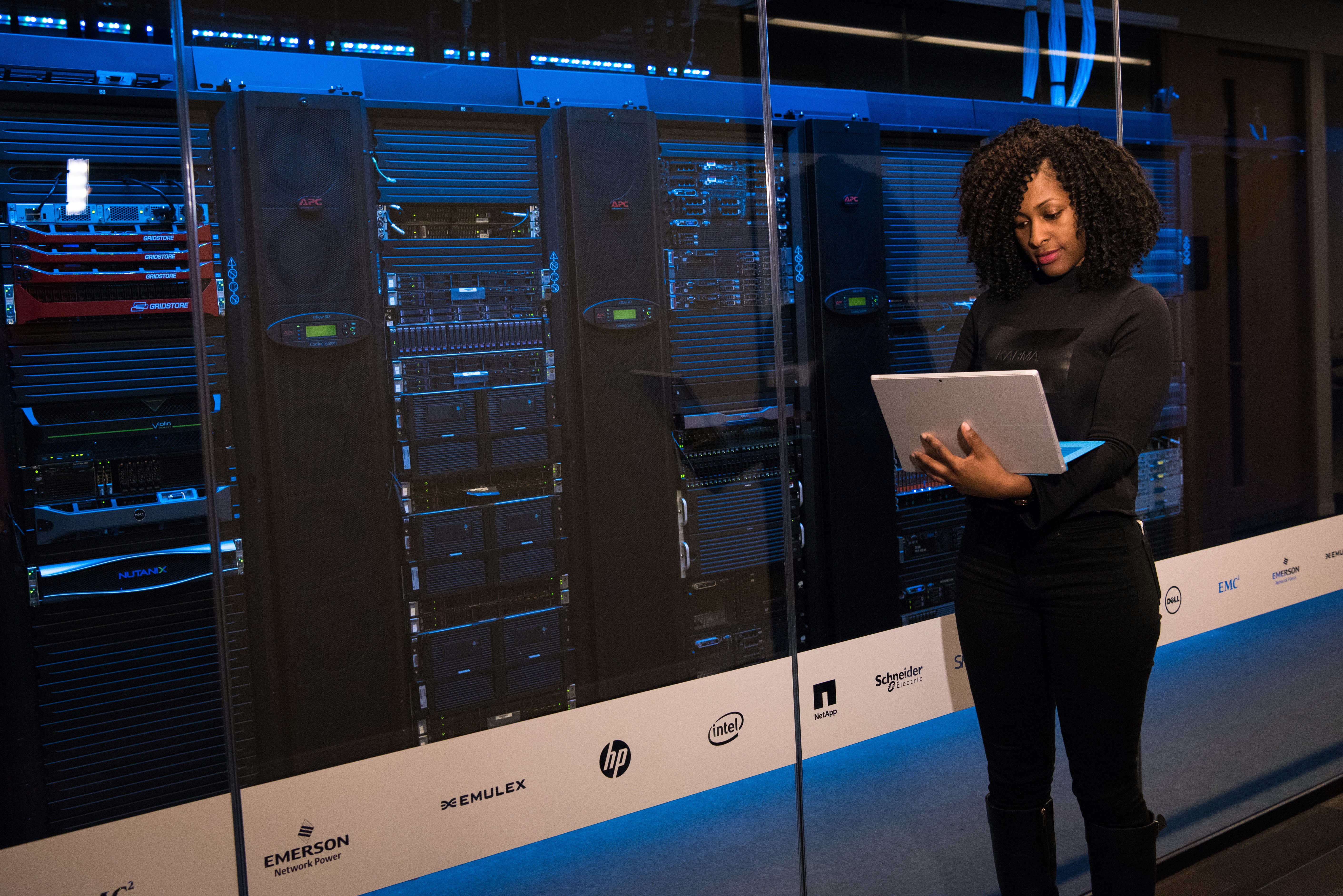 Woman in front of glass wall covering large stacks of hardware.